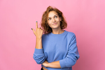 Fototapeta na wymiar Young Georgian woman isolated on pink background pointing with the index finger a great idea