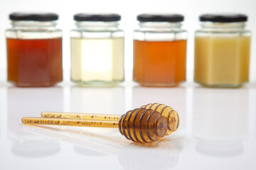 Hexagonal jars with different types and colors of fresh flower honey and a honey spoon. vitamin...