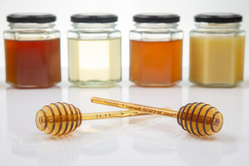 Hexagonal jars with different types and colors of fresh flower honey and a honey spoon. vitamin...