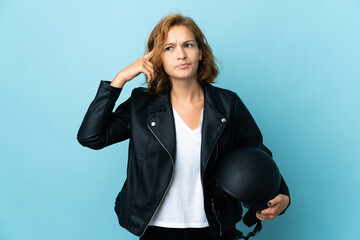 Georgian girl holding a motorcycle helmet isolated on blue background having doubts and thinking