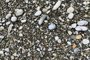 low tide washed pebble stones beach rocks close up view with sand and shadows