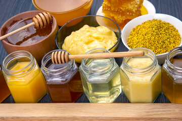 Hexagonal jars with different types and colors of fresh flower honey, spoon, pollen and comb honey. vitamin food for health and life