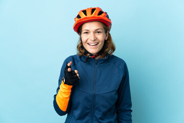 Young cyclist woman isolated on blue background surprised and pointing front