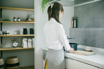 きれいなキッチンで女性が一人鍋の蓋を持ち上げている　woman kitchen - obrazy, fototapety, plakaty