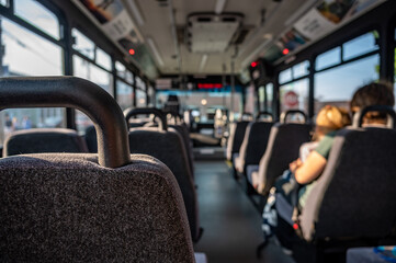 Focus on an empty seat in a bus with only a single mother and child in the distance. 