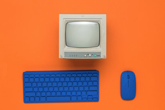 A gray monitor and a blue keyboard and mouse on an orange background.
