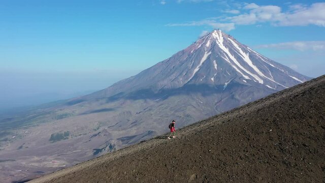 traveler woman walking along the top of the Avachinsky volcano video. Kamchatka, active volcano, red soil