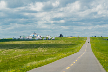 Fototapeta na wymiar A road on green grassland during summer time.