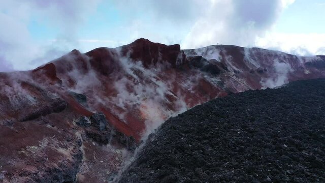 Avachinsky drone volcano summit video. Kamchatka, active volcano, red soil, steam, solidified black lava, sulfur