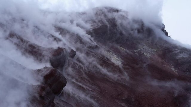 Avachinsky drone volcano summit video. Kamchatka, active volcano, red soil, steam, solidified black lava, sulfur