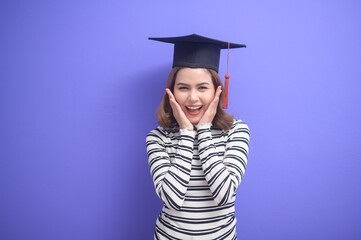 Portrait of young woman graduated over blue background