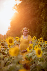 A pregnant women poses for maternity photos in a field of sunflowers in the summertime