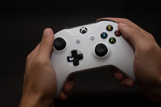 Hands holding Xbox One S controller against black background
