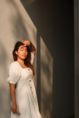 Beautiful asian young woman against white wall with shadow.