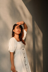 Beautiful asian young woman against white wall with shadow.