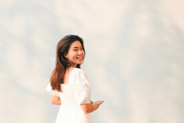Beautiful Asian woman turn back and smile to camera with white wall background.