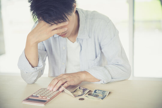 男性が部屋で電卓とお金を出して頭を抱えている　woman money
