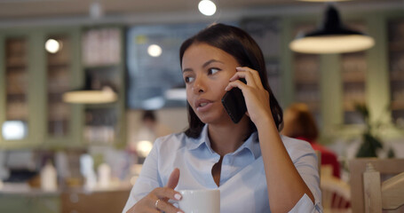 African young businesswoman calling using smartphone relaxing at cafe.