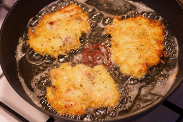 Frying potato pancakes with a piece of fish fillet.