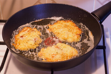 Frying potato pancakes with a piece of fish fillet.