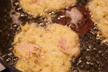 Frying potato pancakes with a piece of fish fillet.