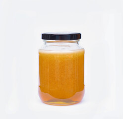 Image closeup isolated yellow honey in the jar glass with black lid is sweet food or dessert from nature on white background with clipping path.