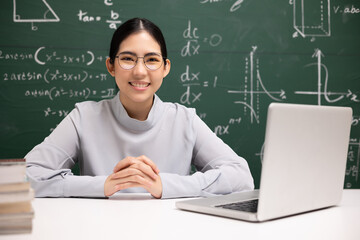 Young asian teacher woman sitting using laptop video conference with student. Female teacher...