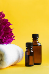 2 jars of brown glass with oil, white towel lie on a yellow background