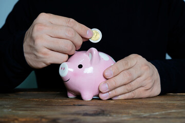 Man putting coin in piggy bank. Saving money concept