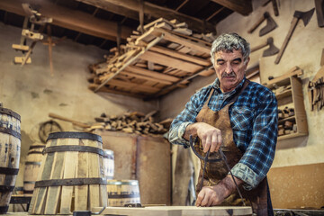 Fototapeta na wymiar Aged man with grey hair does carpentry job in an old workshop