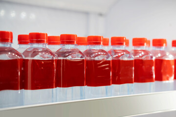 Row of bottles with red beverage on a shelf