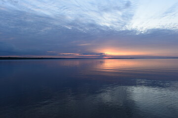 Obraz premium Sunset glow in the clouds on the horizon on the horizon over calm water
