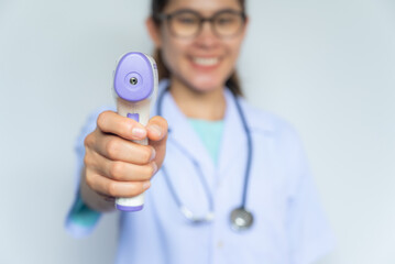 Asian healthcare worker in medical gown holding and aiming an infrared thermometer to camera....