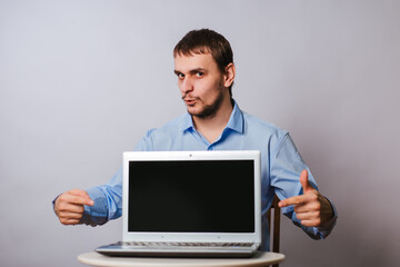 A man in a blue shirt on a white background with a laptop. The guy office worker shows on a blank computer screen. Sample