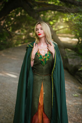 A blonde woman in a green druid cloak and in a fantasy dress with leaves. A sorceress girl in...