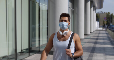 Young sporty man wearing face protective mask on city street
