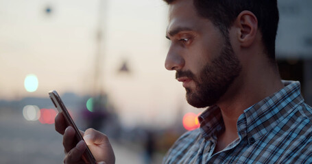 Bokeh close up shot of indian man using smartphone on city street