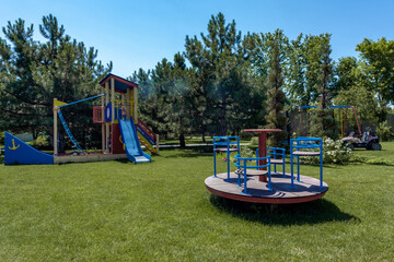 Children boat shaped play complex with slide and carousel on green lawn in summer