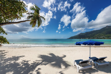 Fototapeta na wymiar Tropical Sunny beach with coco palms and beach umbrella in paradise island
