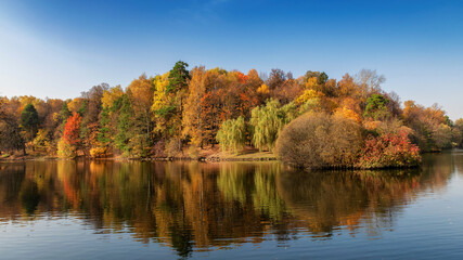 Fototapeta premium Autumn landscape. Autumn trees with colorful leaves reflection in the lake. 