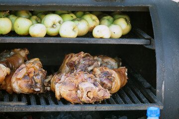 Grilling food. The meat is barbecued with coals. Pork knuckle with apples on the barbecue.