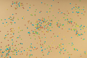 Colorful round sprinkles spilled on yellow paper background. Creative party celebration pattern.