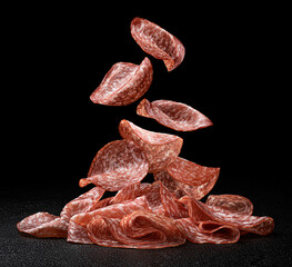 Falling salami slices isolated on black background