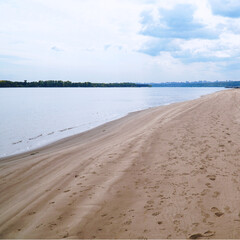 Obraz premium The sandy shore of the big Volga river against the background of a cloudy sky