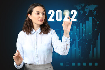 Businesswoman pointing at figure 2022 on dark background