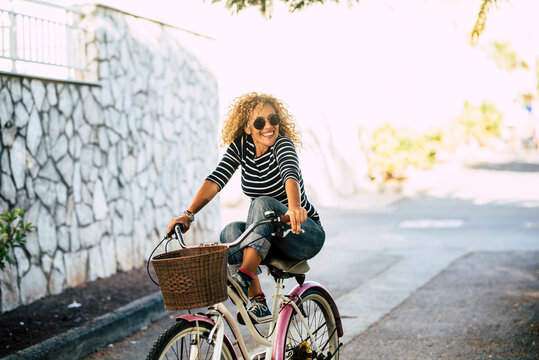 Cheerful happy adult woman enjoy bike ride and have fun alone in city outdoor lifestyle - active female people portrait - active adult lady smile enjoying bike on the road