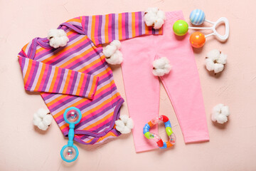 Stylish baby clothes with toys on color background