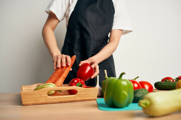 Woman in black apron on the kitchen cutting vegetables diet