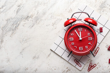 Stylish alarm clock and stationery on grunge background