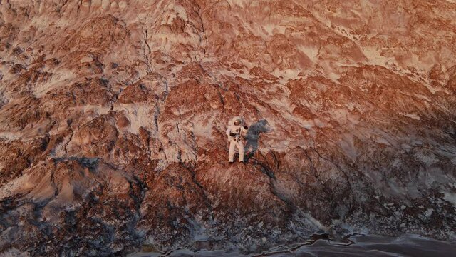 astronaut dancing standing on a rock.the sun is shining.unknown planet. discovery of a new planet. aerial photography